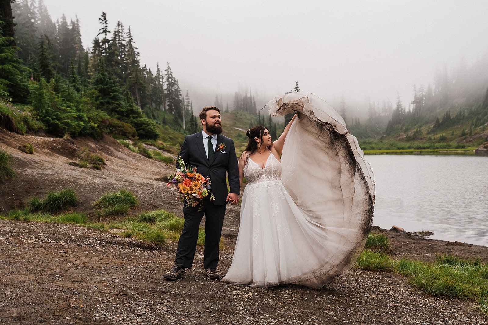 Bride throws her elopement dress train in the air and it catches the wind during her elopement in the North Cascades.