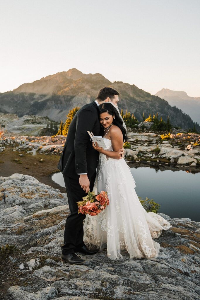 Bride rests her head against groom's shoulder during their elopement vow exchange on a mountain trail.