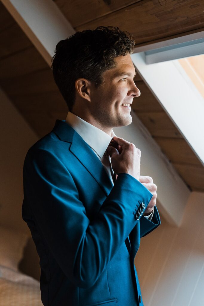 Groom wearing blue suit while getting ready at the Riverbend Retreat in Snoqualmie Pass