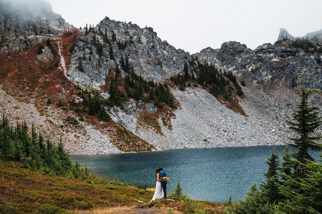 Bride and groom hug and look out at an alpine lake during their elopement in Leavenworth