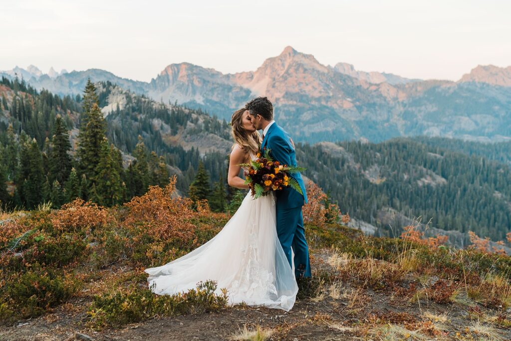 Bride and groom kiss on top of a mountain at sunset during their Washington state elopement