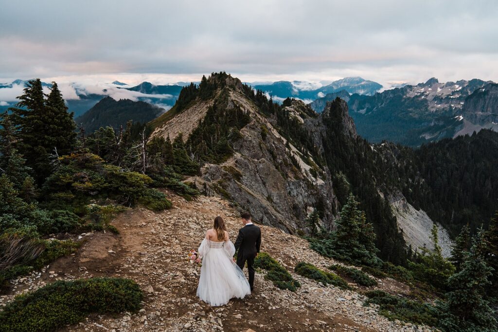 Couple holding hands, walking across the mountain in Mt Rainier National Park at their elopement in Washington