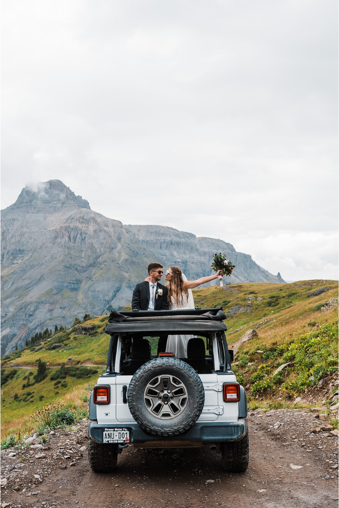 Bride and groom stand in a white Jeep during their mountain elopement photos at Rocky Mountain National Park