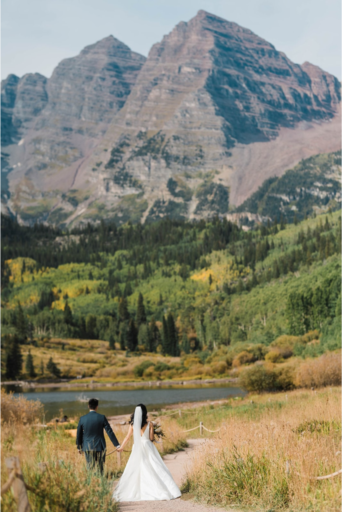 Bride and groom hold hands while walking through Rocky Mountain National Park during their mountain elopement