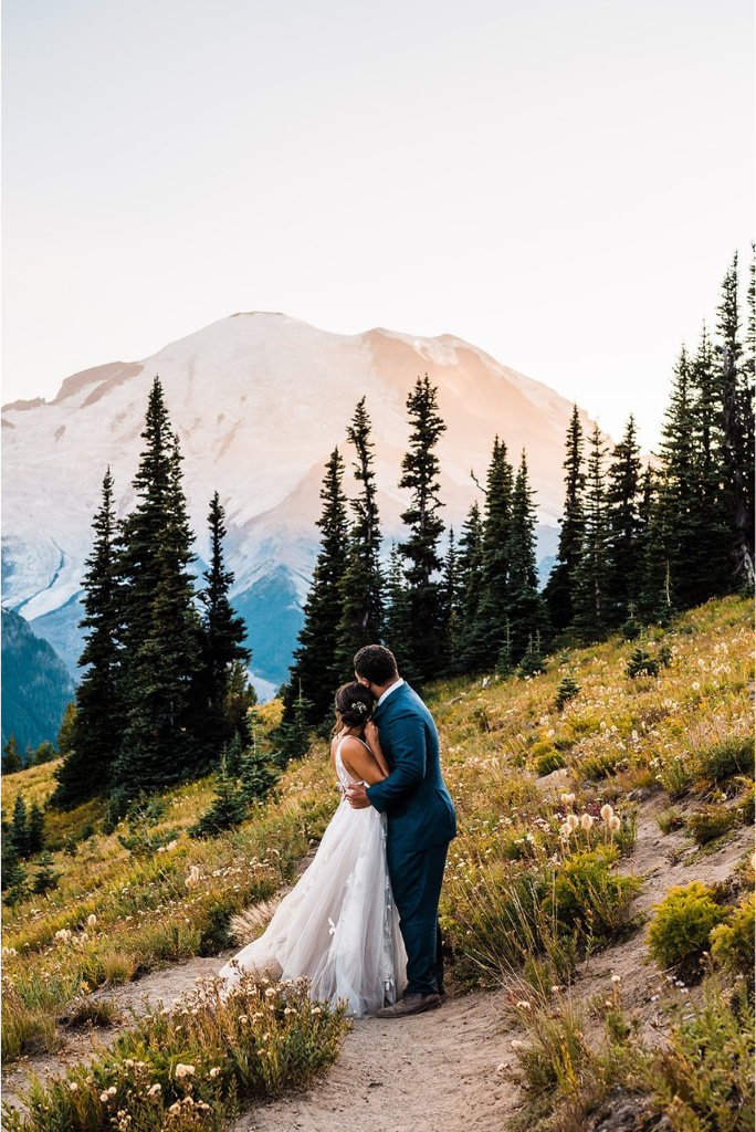 Bride and groom hug while looking out at Mt Rainier during their mountain elopement