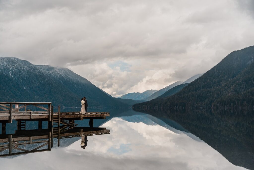 Bride and groom kiss on the dock during their spring elopement at Lake Crescent