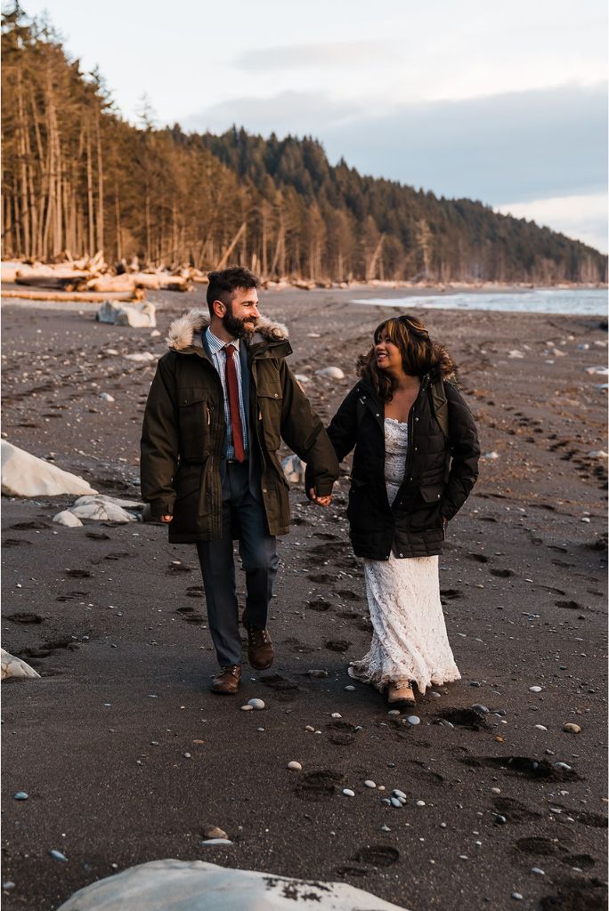 Bride and groom hold hands while walking across the beach at their spring elopement in Washington