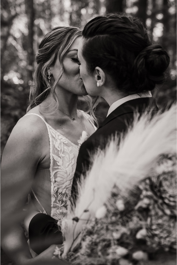 Two brides kiss in the forest during their adventure wedding in Snoqualmie