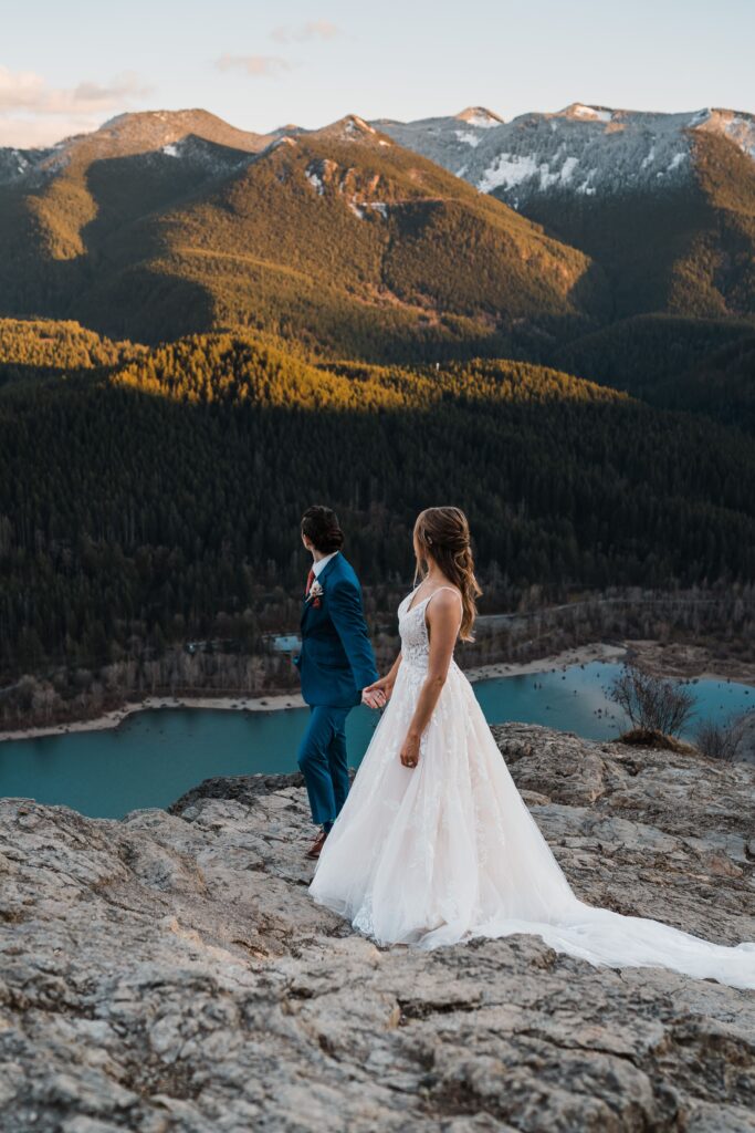Brides look out at an alpine lake during their adventure wedding in Snoqualmie
