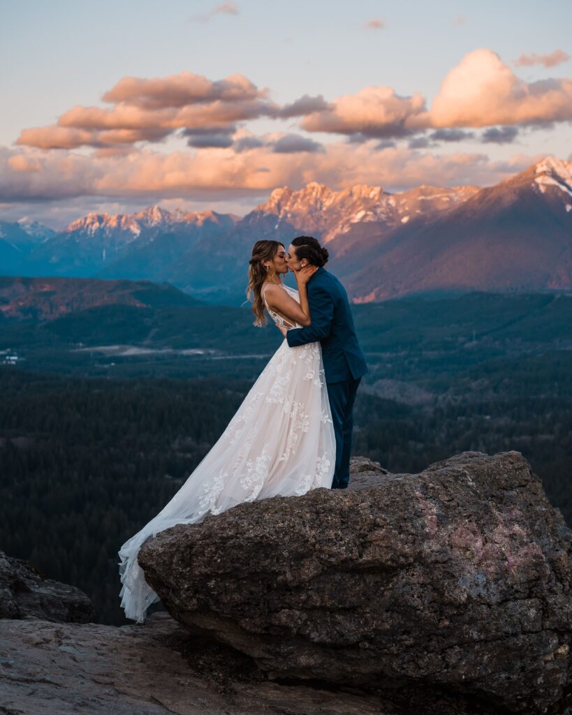 Brides kiss on top of a mountain in Snoqualmie at sunset during their adventure wedding photos