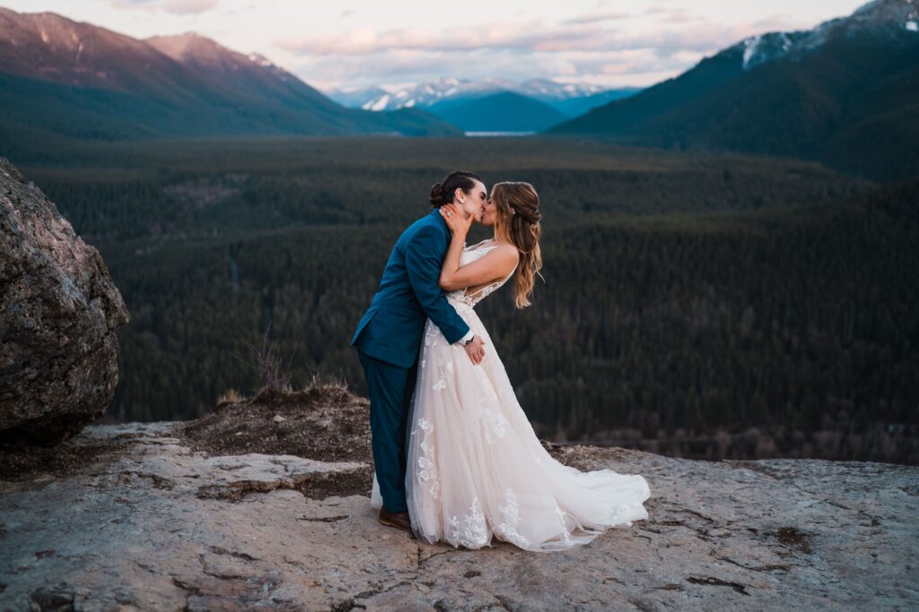 Two brides kiss on a mountain during adventure wedding portraits in Snoqualmie