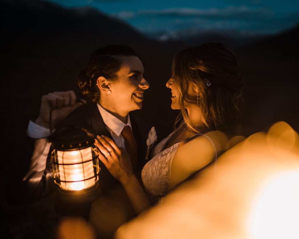 Two brides hold lanterns at blue hour during their adventure wedding photos in Snoqualmie