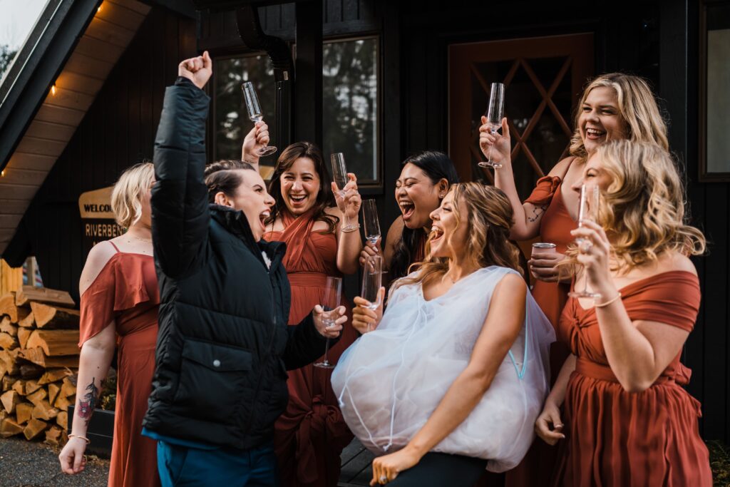 Brides and bridesmaids cheer and drink champagne at The Riverbend Retreat cabin