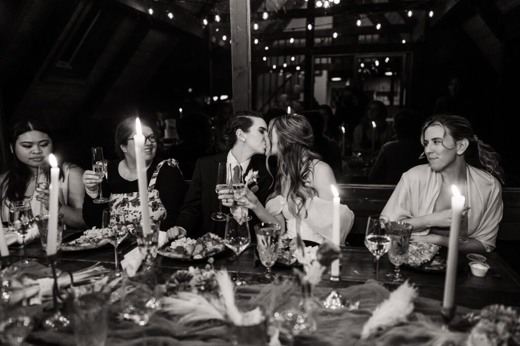 Brides kiss at their reception dinner at The Riverbend Retreat in Snoqualmie