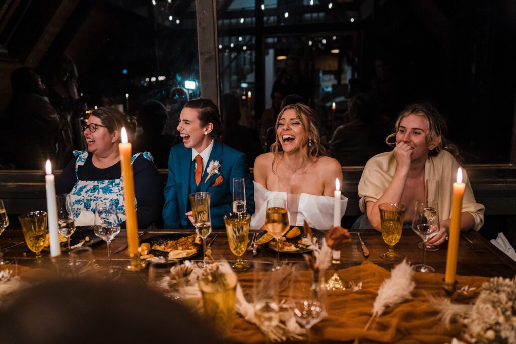 Brides laugh with guests at their adventure wedding reception