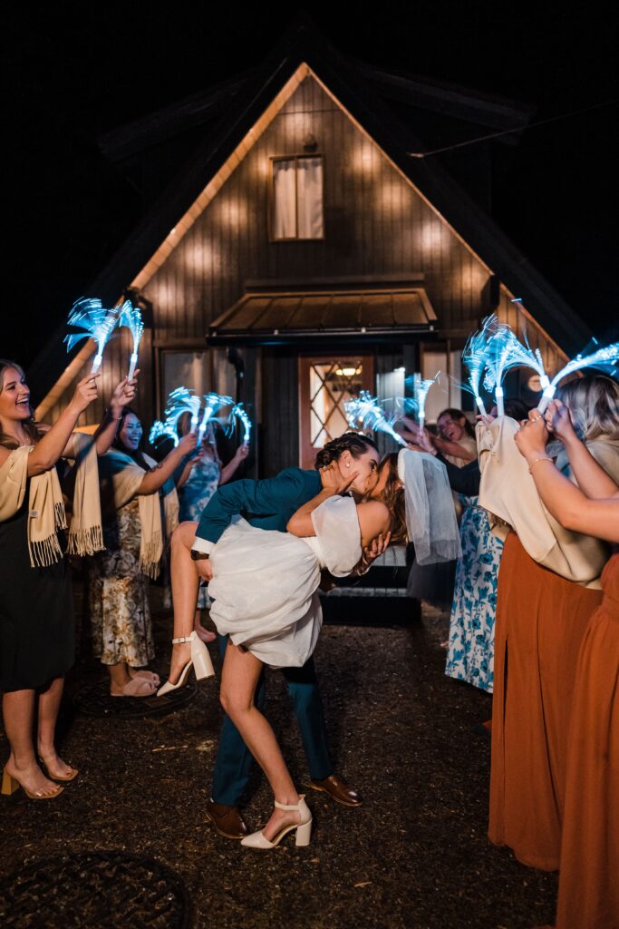 Brides dip for a kiss during their adventure wedding exit