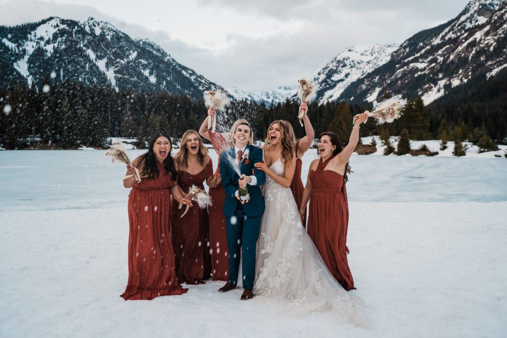 Brides spray champagne while bridesmaids cheer in the background