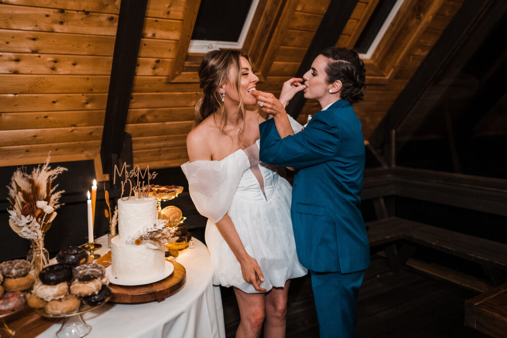 Brides feed each other cake during their adventure wedding celebration