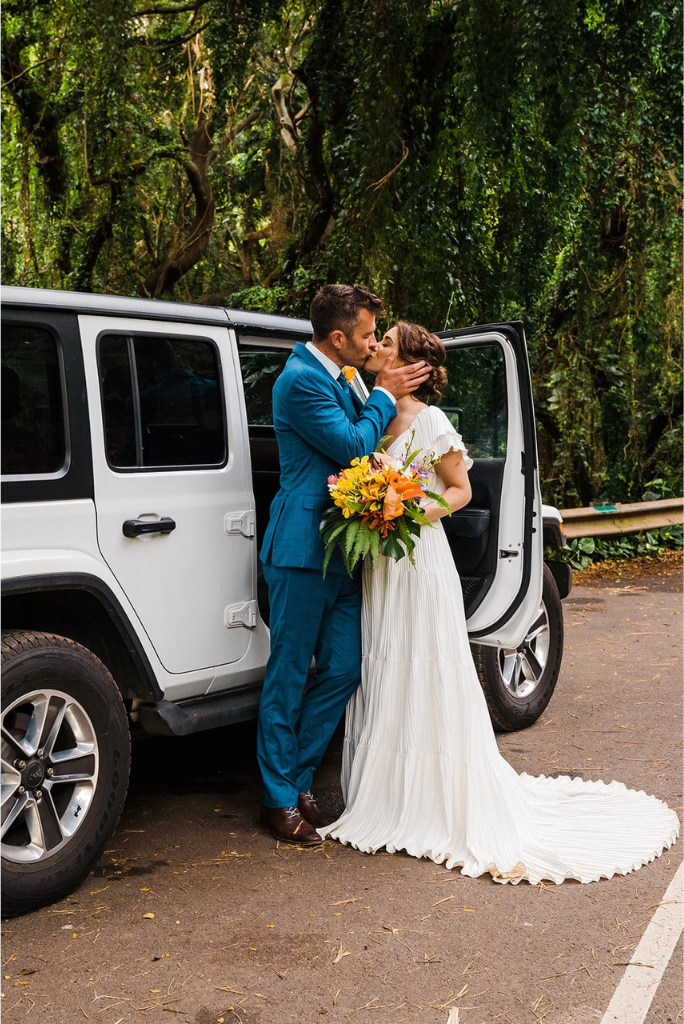 Bride and groom kiss next to a white jeep at their Hawaii elopement