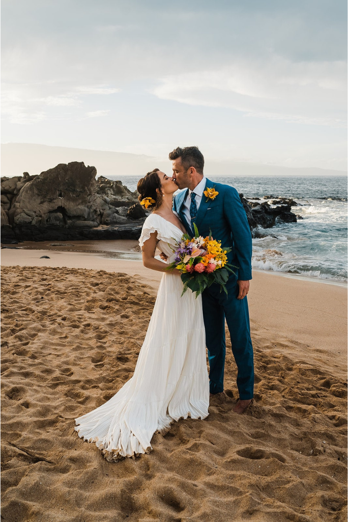 Bride and groom kiss on the beach before their elopement ceremony on Maui