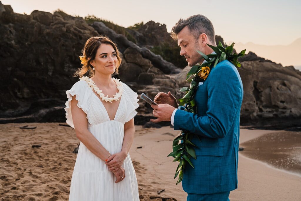 Groom reads vows on the beach during Hawaii elopement ceremony at sunset