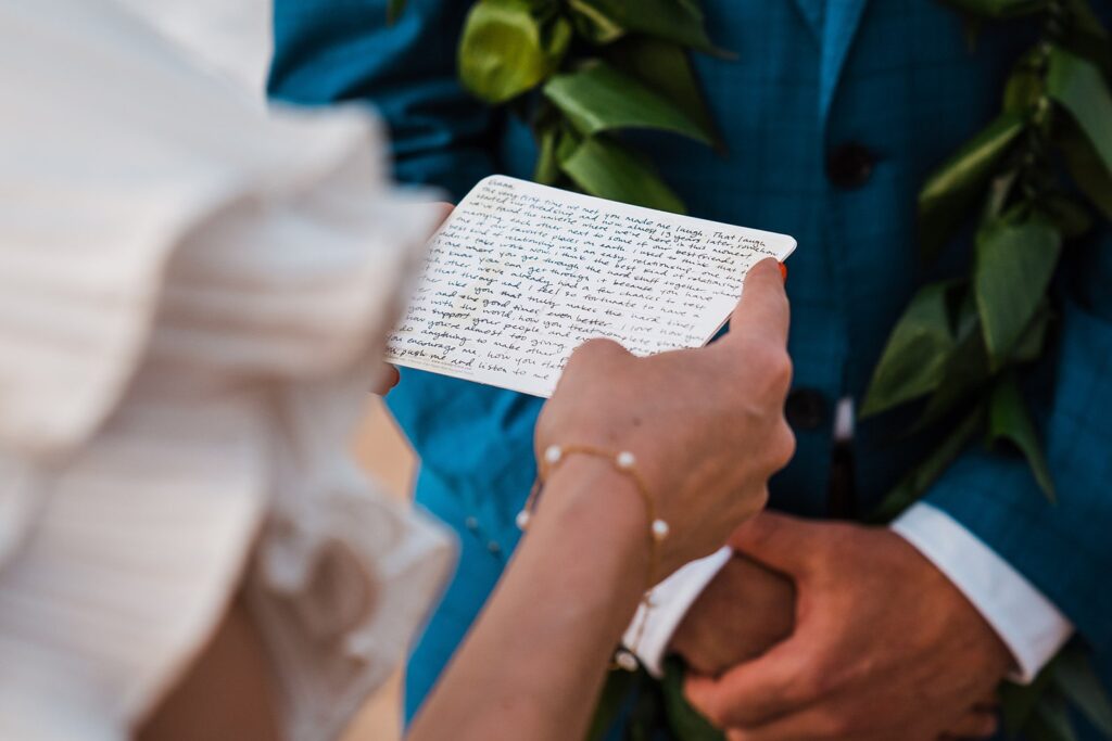 Bride reading personal vows of handwritten card during Maui elopement ceremony on the beach