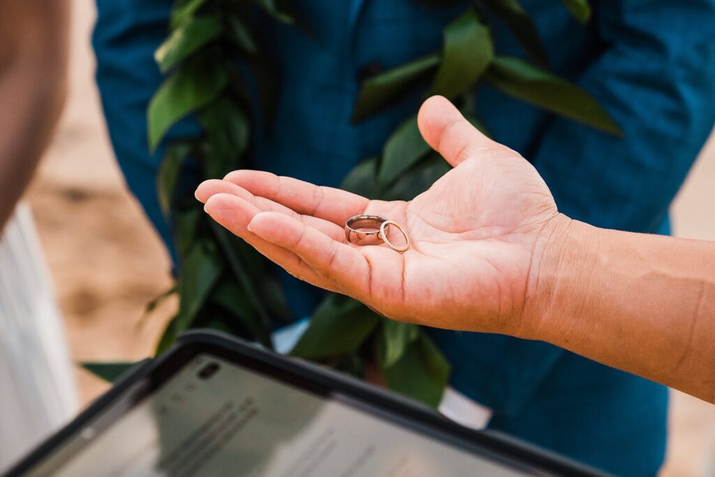Officiant hands over wedding bands during Maui elopement ceremony on the beach