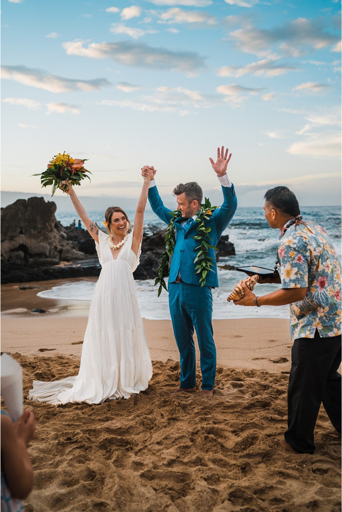 Bride and groom cheer after small intimate elopement ceremony on the beach in Maui