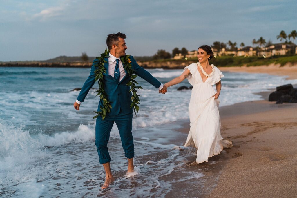 Bride and groom run into the ocean during their Hawaii elopement at sunset