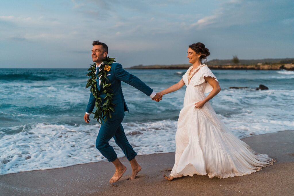 Bride and groom run across the beach after their elopement in Hawaii