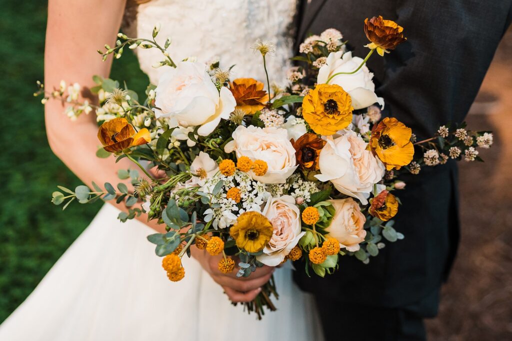 Bride holding white and mustard floral bouquet 