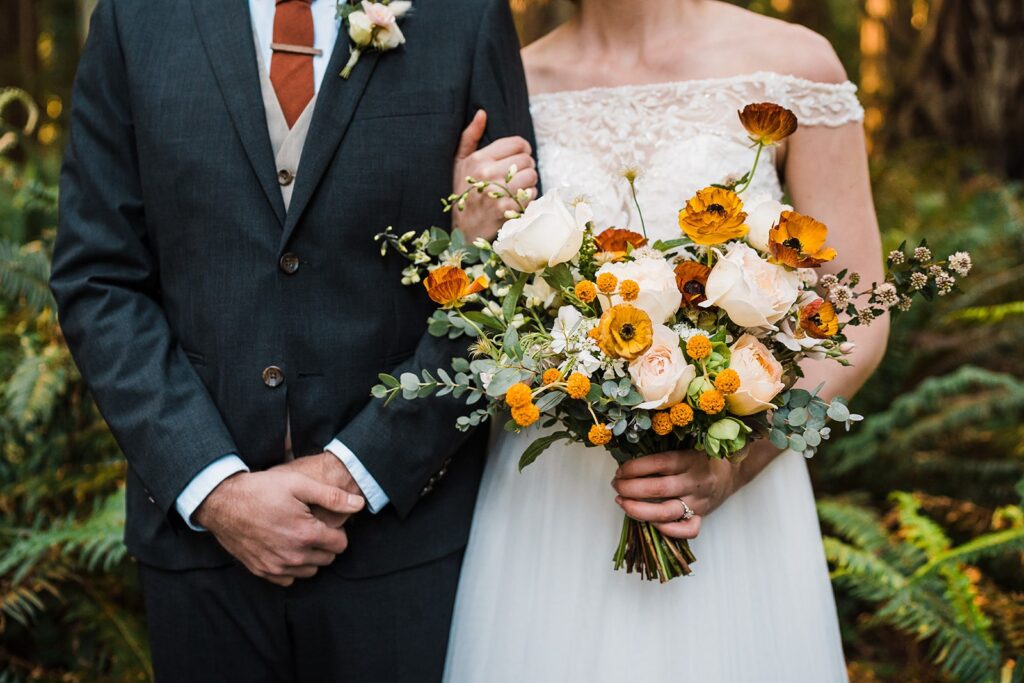 Bride holds a white and mustard yellow floral bouquet during her Redwoods elopement in California