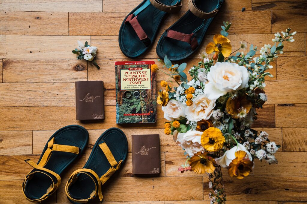 White and mustard yellow floral bouquet with teva sandals and brown leather bound vow books