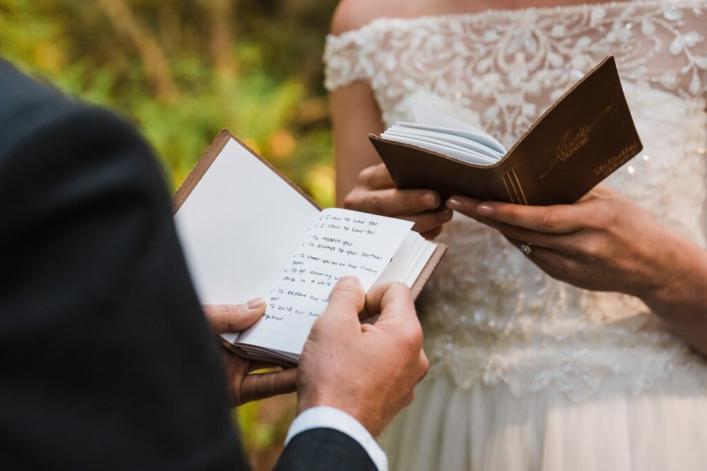 Bride and groom read vows from brown leather vow books