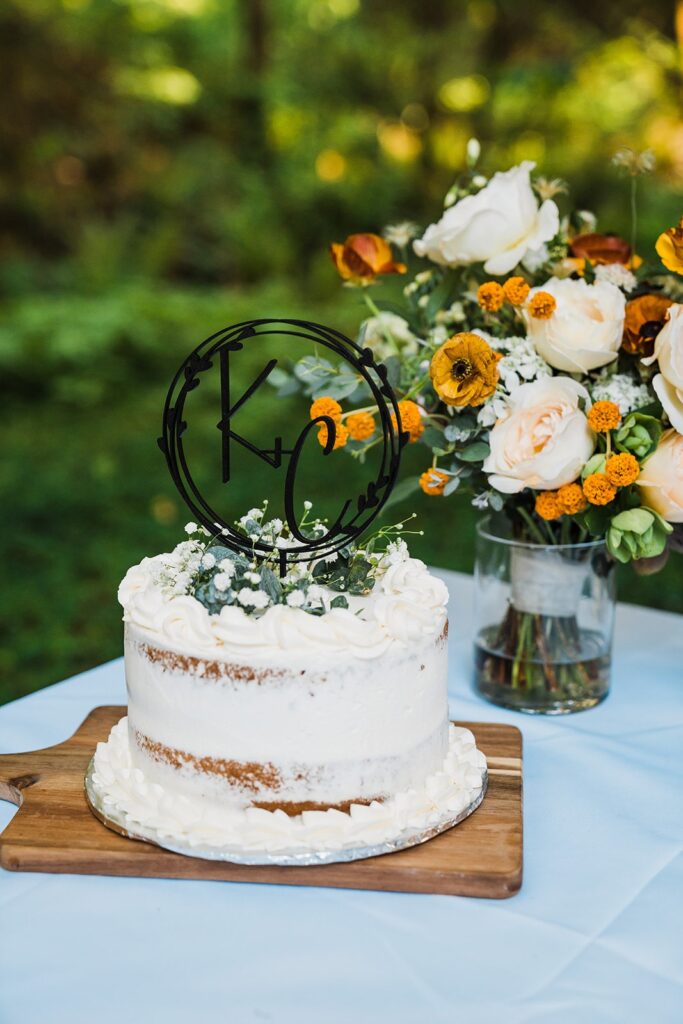 White wedding cake with white and mustard yellow wedding flowers