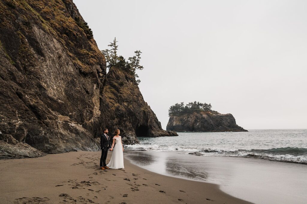 Bride and groom hold hands on the beach during sunset elopement photos in Oregon