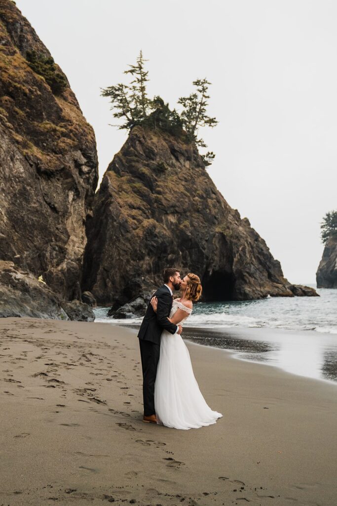 Bride and groom kiss on the beach during their sunset elopement photos in Oregon