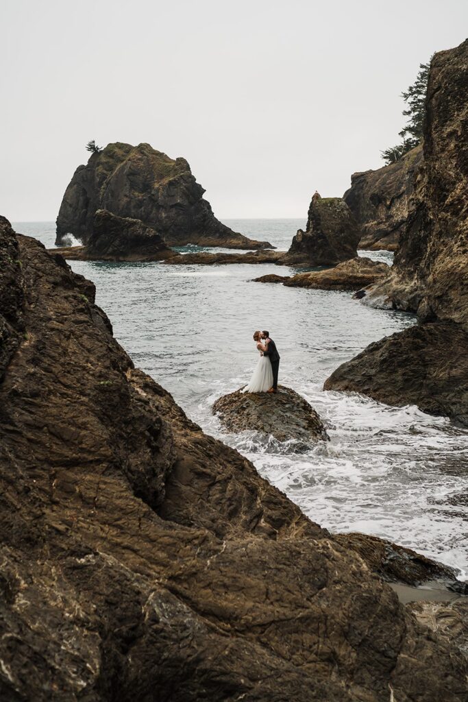 Bride and groom kiss on a rock on the Oregon Coast