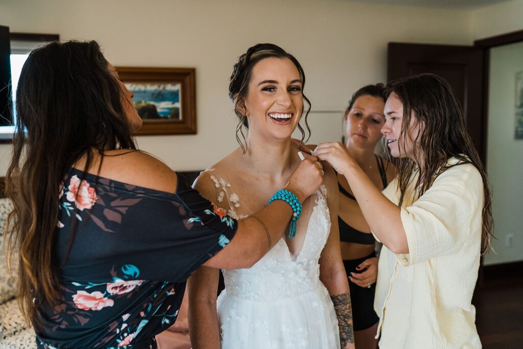 Family helping bride get into her wedding dress for Kauai wedding