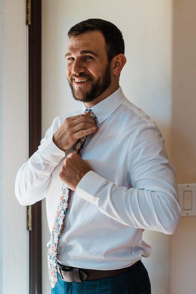 Groom adjusting tie while getting ready for two-day wedding on Kauai