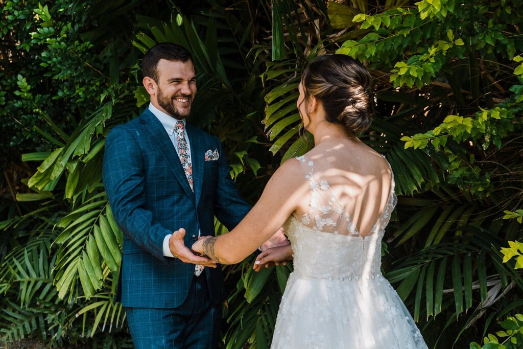 Bride and groom hold hands and smile during first look in Kauai