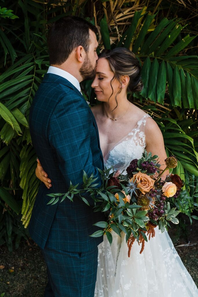 Groom kisses bride on the forehead during wedding first look on Kauai