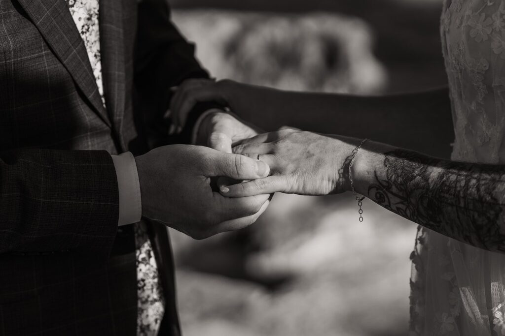Groom slips ring onto bride's finger during beach wedding ceremony on Kauai