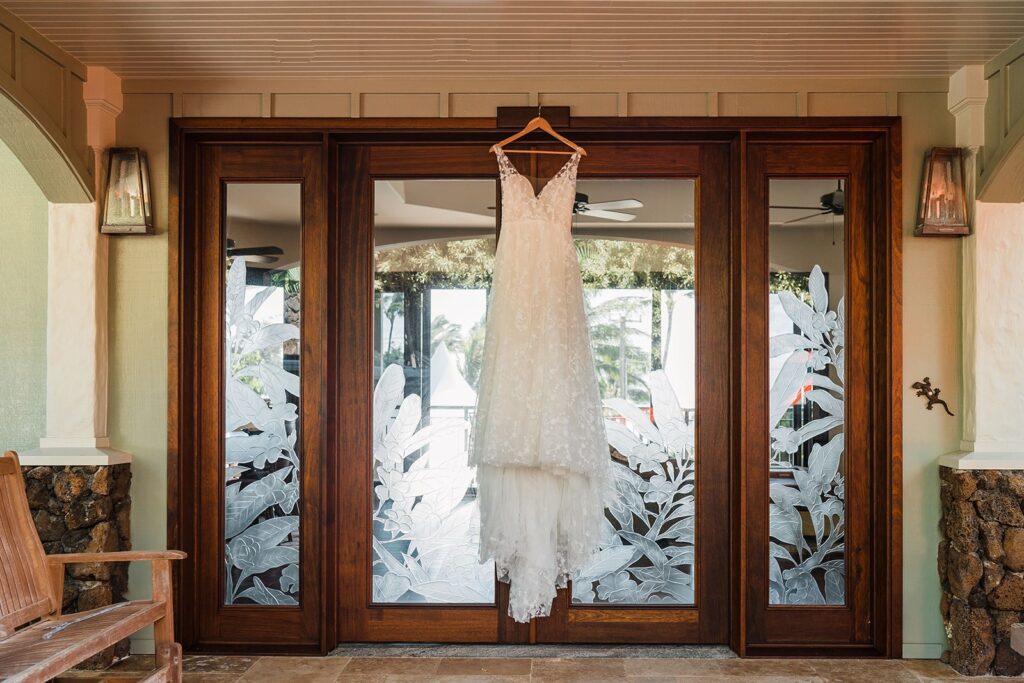 White sleeveless wedding dress hanging from glass door on cabin rental in Kauai