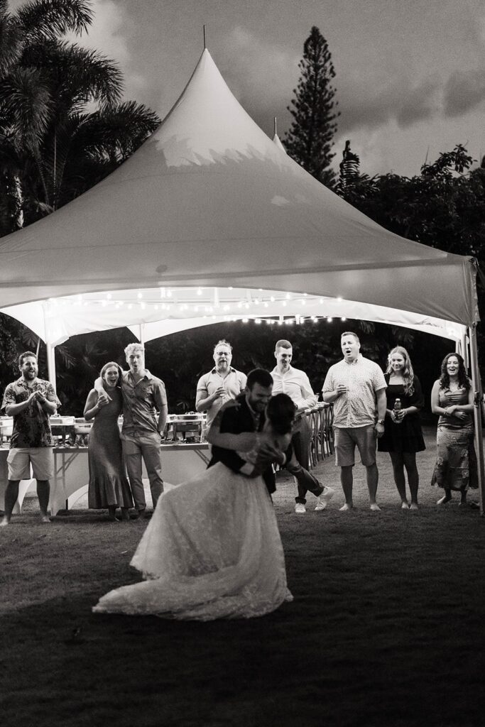 Groom dips bride for a kiss during their wedding first dance in Kauai