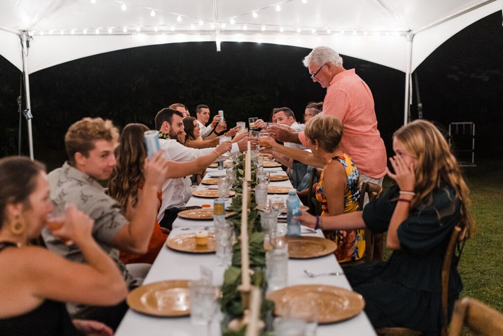 Guests toast at outdoor wedding reception in Kauai