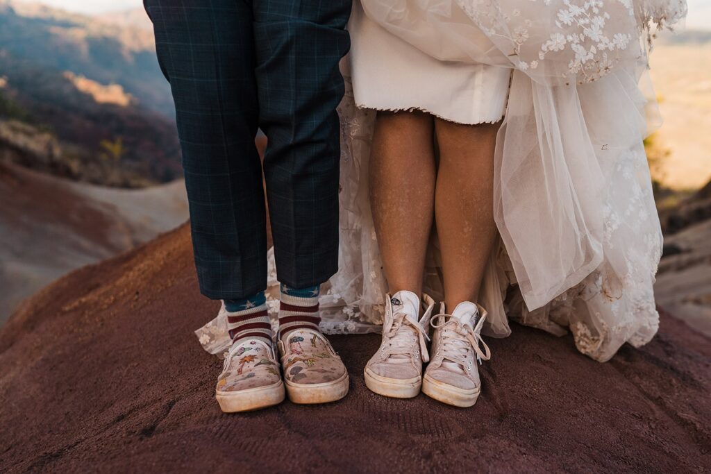 Bride and groom wear vans and Converse shoes while taking wedding photos at Waimea Canyon