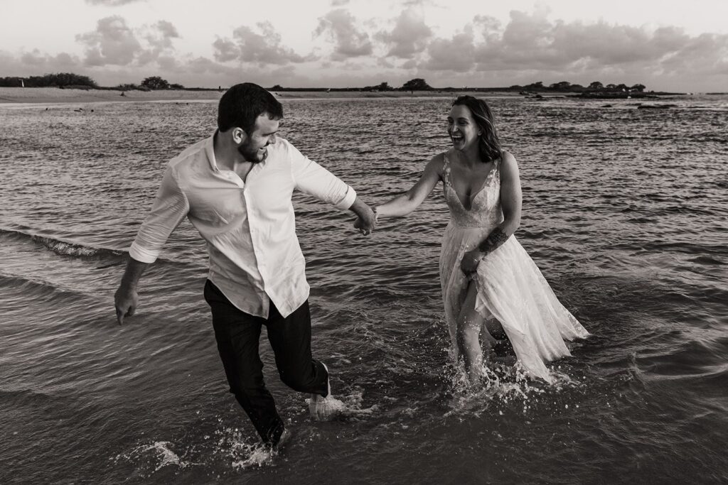 Bride and groom run through the ocean during their two-day wedding on Kauai