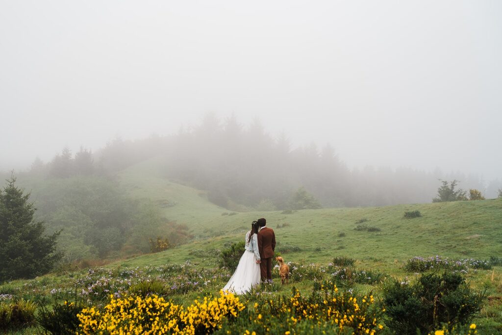 Bride and groom hold hands on a foggy hill during their Crook Point elopement first look at sunrise
