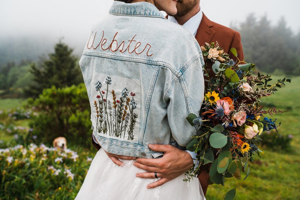 Bride wearing custom embroidered denim jacket for her first look wedding photos at Crook Point